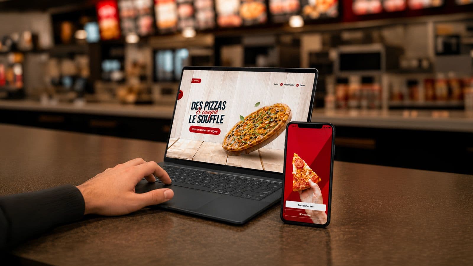 Site de commande d'un restaurant affiché sur un ordinateur portable et sur un mobile, posés sur un comptoir
